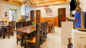 A dining area with wooden furniture, a ceiling fan, and a wall sign. - Super Collection O Mall Road (Dehradun)