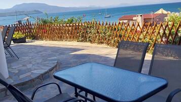 Eine Außenpatio mit Tisch und Stühlen, ein Holzzaun und Blick auf das Meer mit Booten.