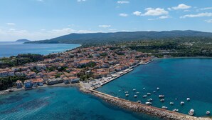 Une ville côtière dotée d’un port de plaisance, de bâtiments aux toits recouverts de tuiles rouges et d’une mer d’un bleu limpide.