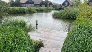 A wooden dock leading to a canal with houses in the background. - Luxury Beach Villa in Makkum with Sauna (Makkum)