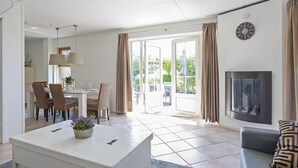A modern living room with a dining area, a fireplace, and a large window. - Luxury Beach Villa in Makkum with Sauna (Makkum)