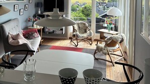 Una sala de estar moderna con televisor, asientos y vistas a un barrio residencial.