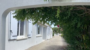 Kapea polku johtaa riviin valkoisia rakennuksia, joissa on useita ikkunoita, ja polun ympärillä on vehreää kasvillisuutta.