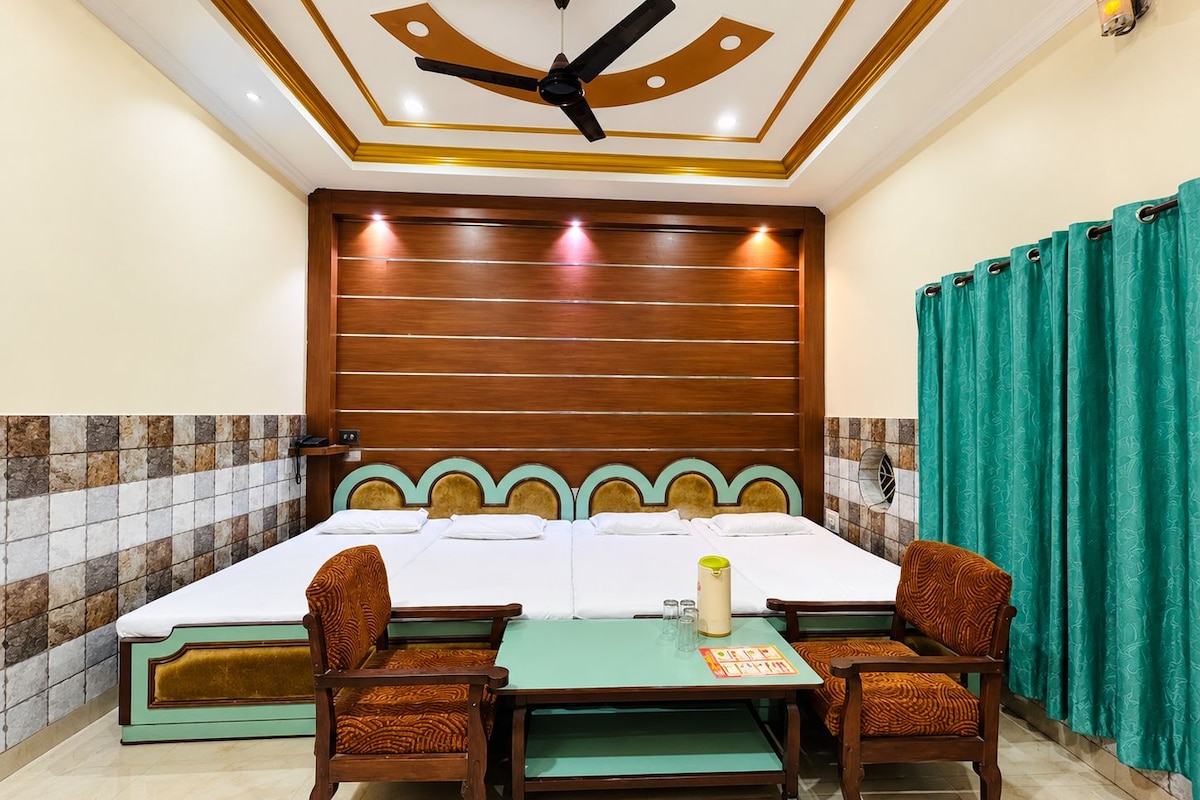 Una habitación de hotel con una cama grande, dos sillas, una mesa y un ventilador de techo.