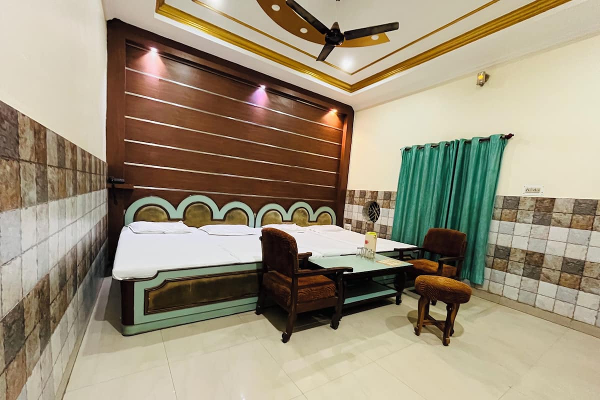 A hotel room with a bed, a desk, two chairs, a ceiling fan, and a window with curtains.