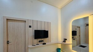 A modern bathroom with a wooden vanity, a mounted TV, and a mirror with a light.