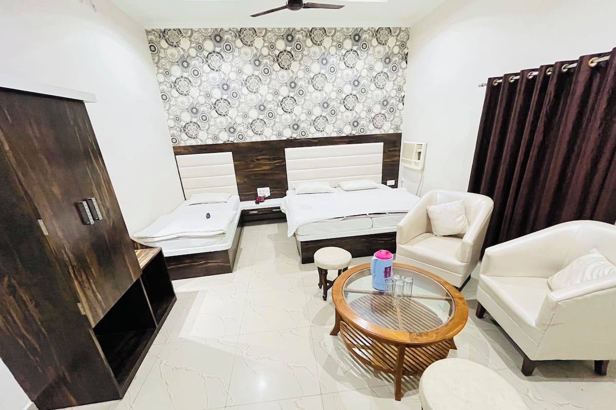 A hotel room with a bed, two sofas, a coffee table, and a wardrobe.