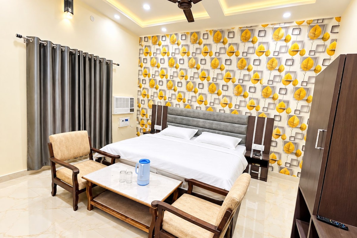 Una habitación de hotel con cama, dos sillones, una mesita de centro, un armario y un ventilador de techo.