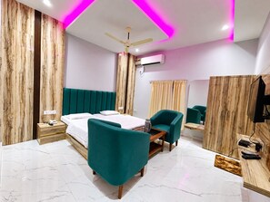 Una habitación de hotel moderna con una cama, un escritorio, una silla, un ventilador de techo, un equipo de aire acondicionado y un televisor.