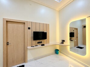 Un baño moderno con puerta de madera, televisor montado, espejo con iluminación integrada y suelo de mármol.
