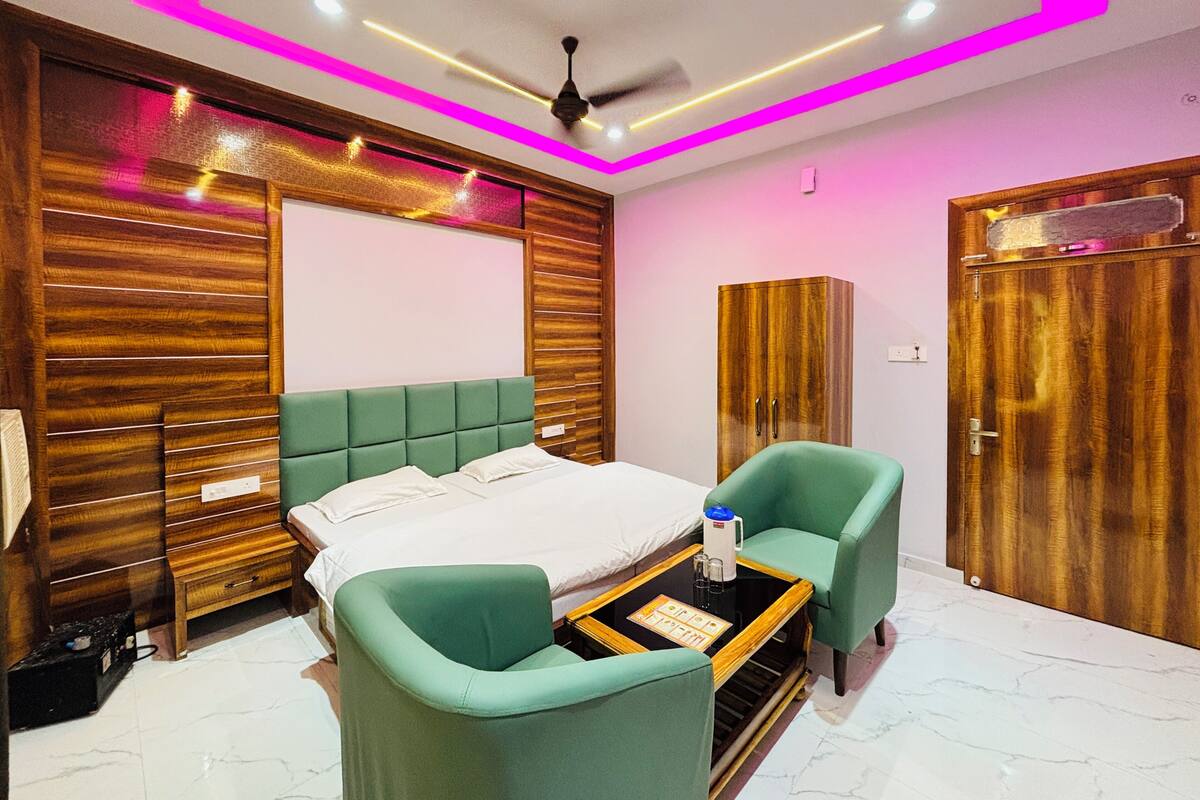A hotel room with a bed, two chairs, a desk, and a wardrobe.