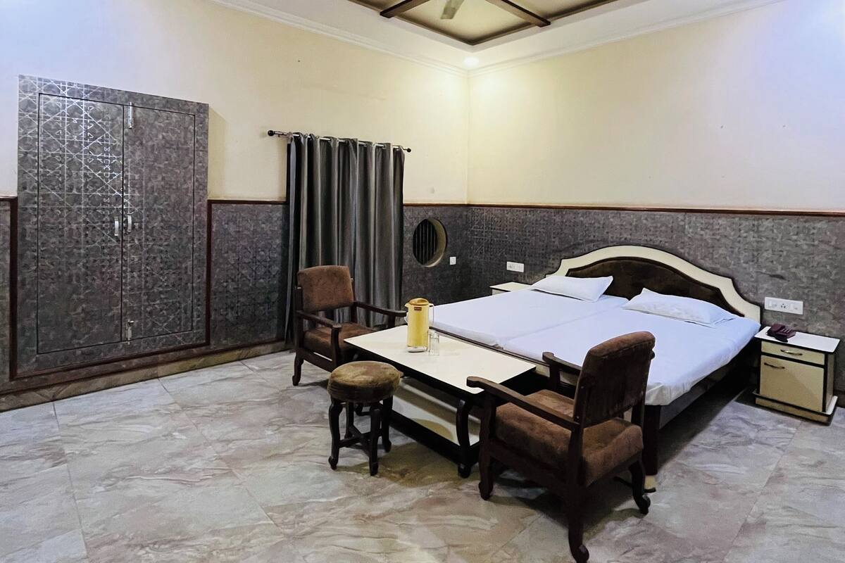 A hotel room with a bed, a desk, a chair, a wardrobe, and a ceiling fan.