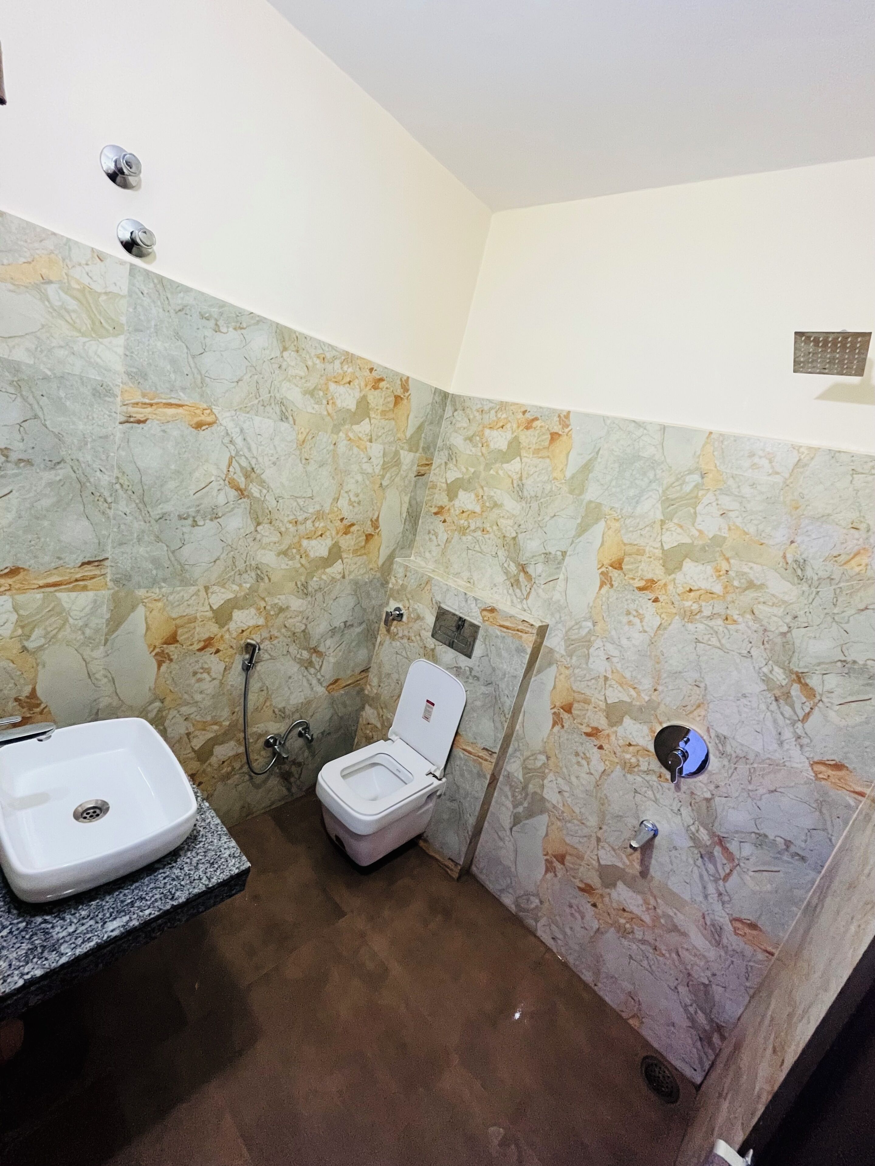 A bathroom with a marble wall, a sink, and a toilet.