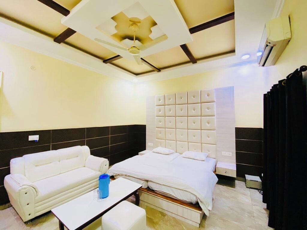 Una habitación de hotel con cama, sofá, mesa y ventilador de techo.