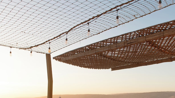 A rooftop terrace with a seating area, a table, and a view of the cityscape. - The Lodge (Aourir)