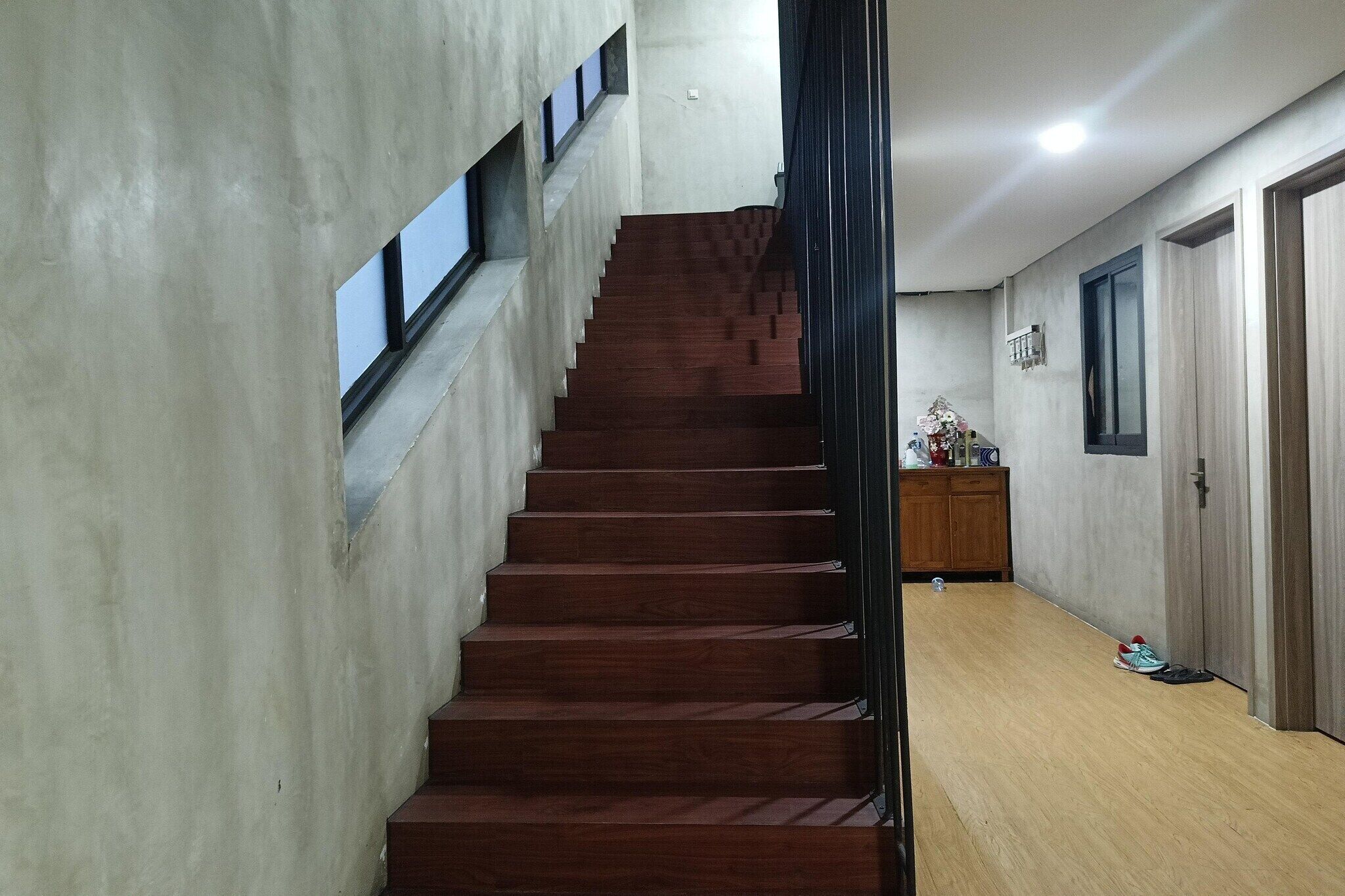 Un escalier avec des marches en bois menant à un palier, une armoire en bois et une porte située sur le côté droit.