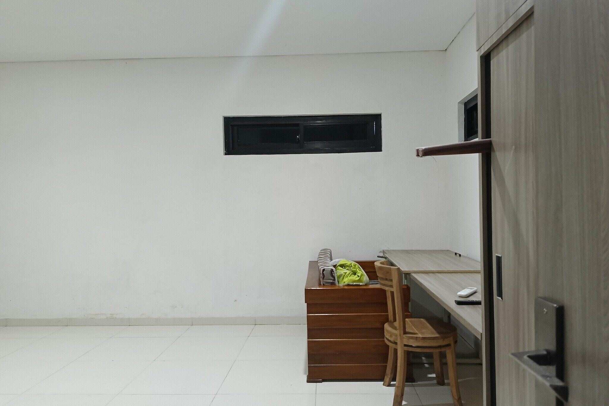 A room with a desk, chair, and a small window.