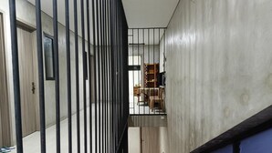 A corridor with a metal railing, a wooden door, and a staircase leading to an upper level. - Smart Solo Stay Near RSUD Haji (Makassar)