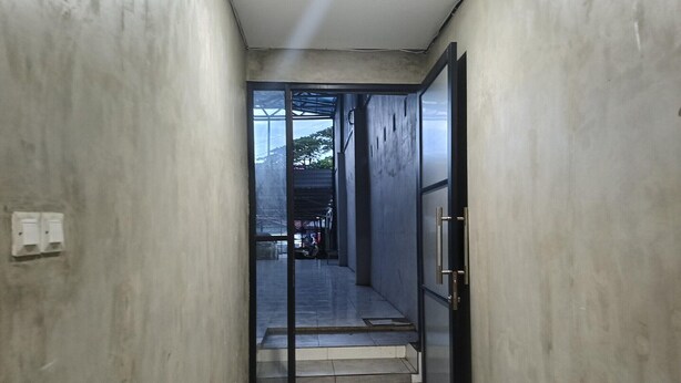 A narrow hallway with a glass door leading to a staircase. - Smart Solo Stay Near RSUD Haji (Makassar)