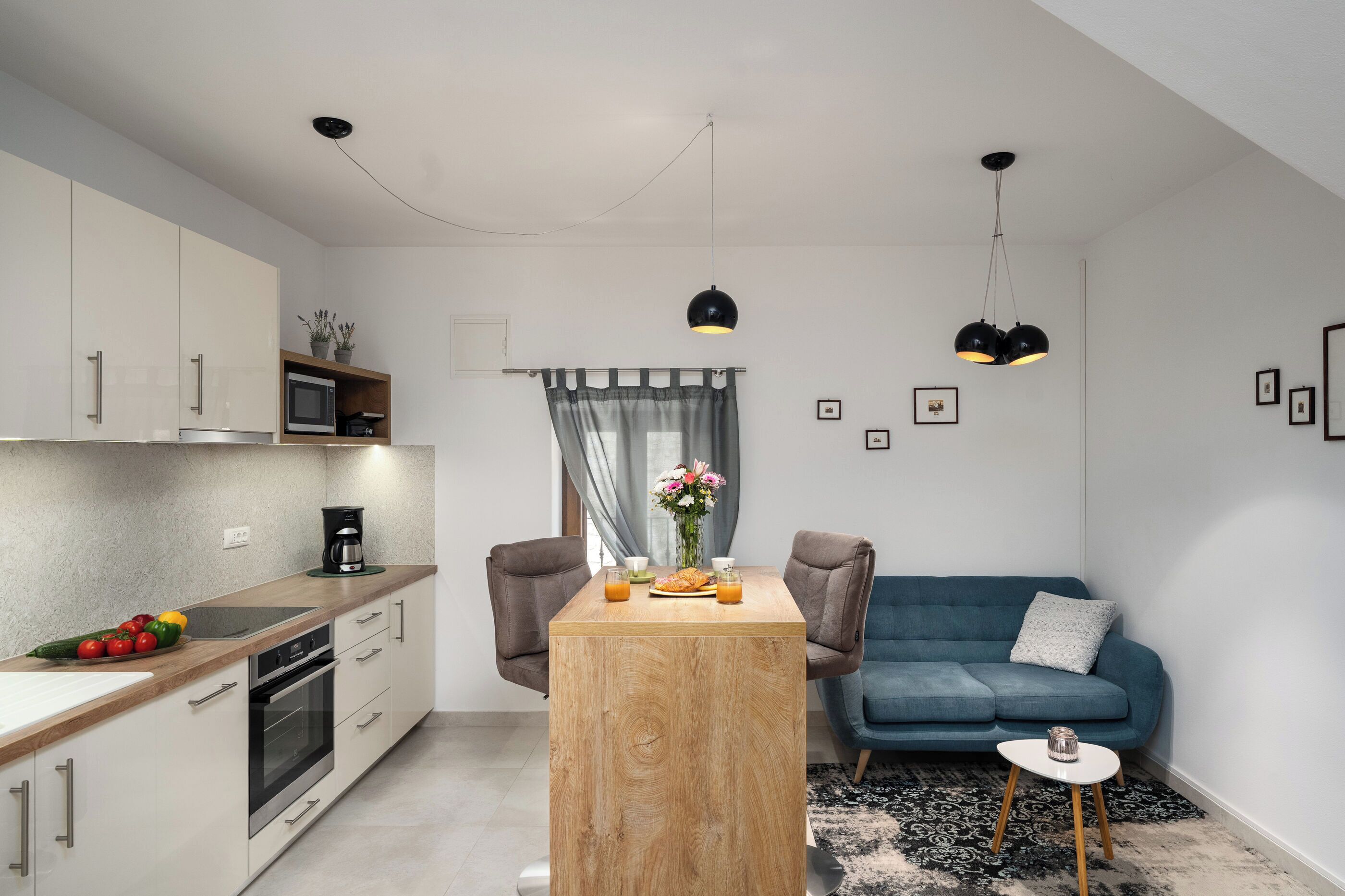 A modern kitchen with a dining table, a blue sofa, and a small side table.
