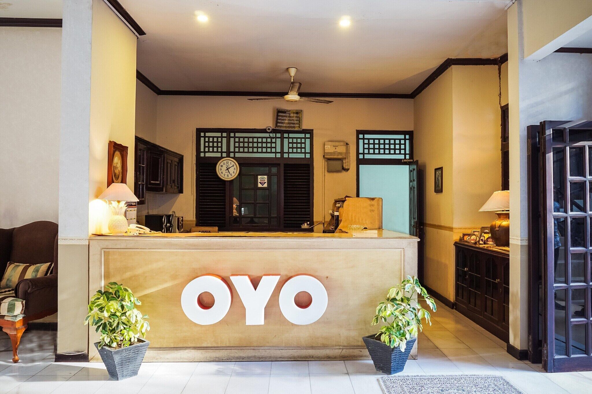 Una reception con la scritta 'OYO', una ventola a soffitto e finestre in stile tradizionale.