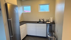 Cocina moderna con refrigerador de acero inoxidable, un lavamanos y una ventana.