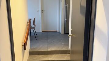 A staircase leading to a door with a handrail, a chair, and a fire alarm on the wall.