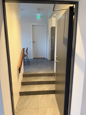 A staircase leading to a door with a handrail, a chair, and a fire alarm on the wall.