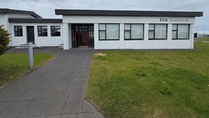 Una casa de huéspedes moderna con techo plano, ventanas amplias y entrada pavimentada.