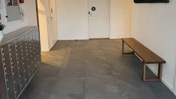 Eine Hotelhalle mit einer Bank, einer Tür mit einer Nummer, einem Kleiderständer und einer Deckenleuchte.