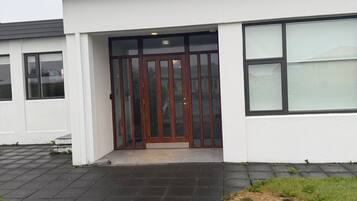 A modern building with a flat roof, large windows, and a central entrance with a glass door.