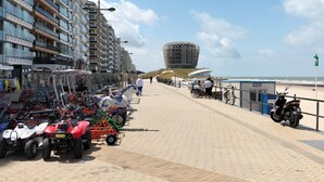 Ein gepflasterter Weg mit Quads, ein markantes, kugelförmiges Gebäude und ein Strand im Hintergrund.