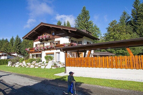 A chalet-style building with a balcony, a wooden fence, and a clear sky.