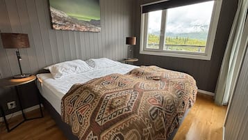 Une chambre à coucher avec un lit, une fenêtre donnant sur un beau paysage, une lampe et un tableau accroché au mur.