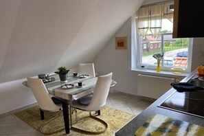 Ein Essbereich mit Tisch, Stühlen und einem Fenster mit Blick auf Gebäude.