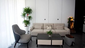 Una sala de estar moderna con un sofá, un sillón estampado, una mesa de centro y una planta en maceta.