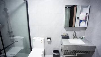 Un bagno moderno con doccia in vetro, un WC bianco, un lavandino con specchio e un cestino.