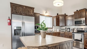 Een moderne keuken met een centraal eiland, houten kastjes, roestvrijstalen apparatuur en een brandblusser.
