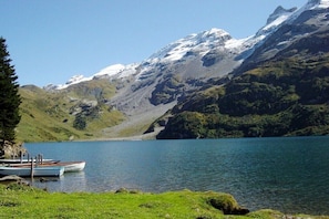 Ein See mit vertäuten Booten, umgeben von Bergen und Grünfläche.