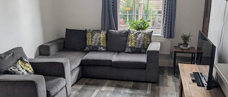 Una sala moderna con un sofá modular, una mesa de centro de madera y un televisor sobre un mueble.