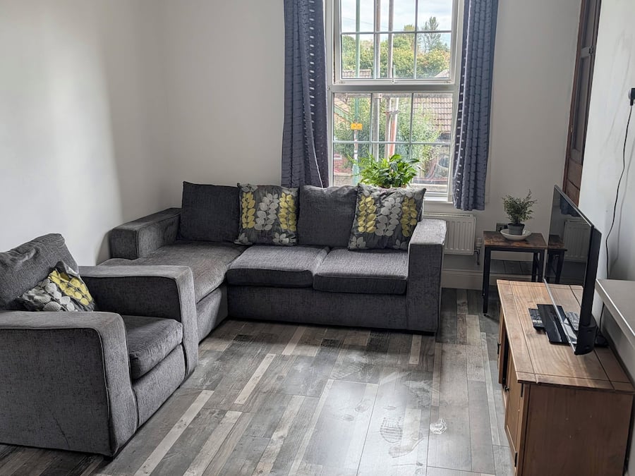 A modern living room with a sectional sofa, a wooden coffee table, and a television on a stand.