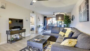 A modern living room with a sofa, coffee table, TV, and ceiling fan. - Community Perks! Phoenix Haven w/ Private Balcony (Phoenix)