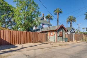 A fenced yard with a house, palm trees, and a clear sky. - 1/2 Mi to Dtwn! Nurse-Ready Rental in Riverside (Riverside)