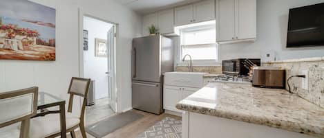 A kitchen with white cabinets, a stainless steel refrigerator, a microwave, and a granite countertop.