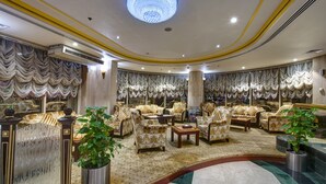 A luxurious lobby with ornate curtains, plush seating, and a grand chandelier.