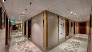 A hotel corridor with a geometric patterned floor, a central column, and doors on both sides.