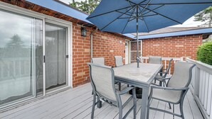 Een overdekt terras met een tafel, stoelen en een grote parasol, plus een schuifpui.