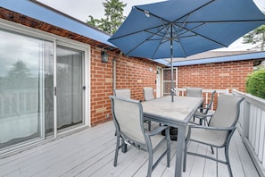 A covered patio with a table and chairs, a large umbrella, and a sliding glass door. - Quiet Home w/ Deck & Water Views in Des Moines (Des Moines)