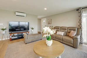 A living room with a TV, sofa, coffee table, and decorative plants. - Quiet Home w/ Deck & Water Views in Des Moines (Des Moines)
