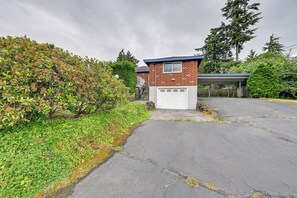 A residential building with a garage, surrounded by greenery and a paved driveway. - Quiet Home w/ Deck & Water Views in Des Moines (Des Moines)